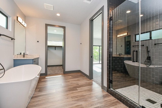 11007 Olde Mint House Ln, Tomball, TX 77375 - bathroom featuring wood finished floors, vanity, a soaking tub, a stall shower, and baseboards