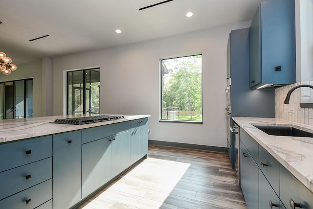 11007 Olde Mint House Ln, Tomball, TX 77375 - kitchen with stainless steel gas cooktop, healthy amount of natural light, a sink, light stone counters, and recessed lighting