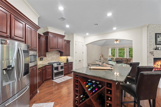 2428 Village Grn, Conroe, TX 77304 - kitchen with appliances with stainless steel finishes, open floor plan, dark wood finished floors, decorative backsplash, and arched walkways