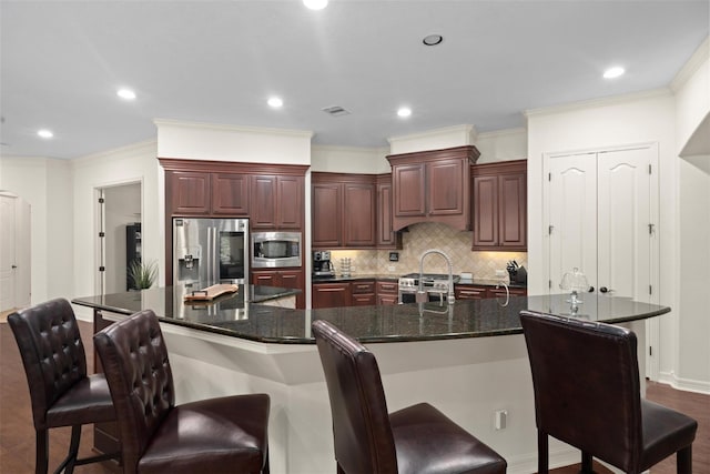 2428 Village Grn, Conroe, TX 77304 - kitchen featuring appliances with stainless steel finishes, tasteful backsplash, ornamental molding, a kitchen bar, and recessed lighting