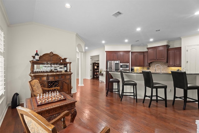 2428 Village Grn, Conroe, TX 77304 - kitchen featuring appliances with stainless steel finishes, ornate columns, a breakfast bar area, dark wood-style floors, and recessed lighting