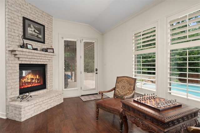 2428 Village Grn, Conroe, TX 77304 - sitting room featuring vaulted ceiling, dark wood-style floors, ornamental molding, a brick fireplace, and baseboards