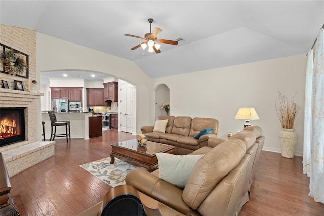 2428 Village Grn, Conroe, TX 77304 - living room featuring lofted ceiling, ceiling fan, wood finished floors, arched walkways, and a fireplace