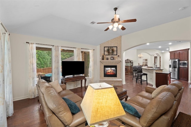 2428 Village Grn, Conroe, TX 77304 - living area with arched walkways, lofted ceiling, a ceiling fan, a fireplace, and wood finished floors