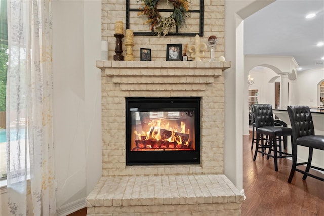 2428 Village Grn, Conroe, TX 77304 - detailed view of arched walkways, wood finished floors, a brick fireplace, crown molding, and recessed lighting