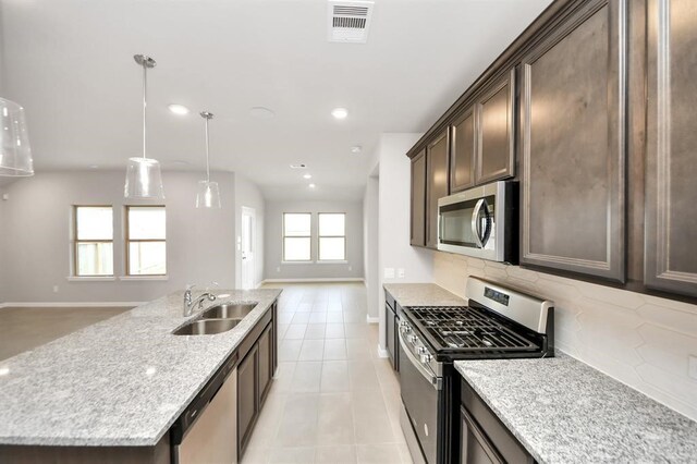 1307 Bonnerjee Dr, Crosby, TX 77532 - kitchen featuring appliances with stainless steel finishes, a sink, open floor plan, dark brown cabinetry, and backsplash