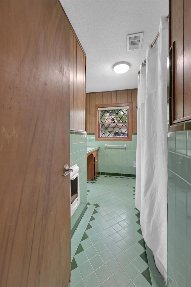 2009 Lamar Dr, Pasadena, TX 77502 - bathroom featuring tile walls, tile patterned floors, heating unit, a textured ceiling, and curtained shower