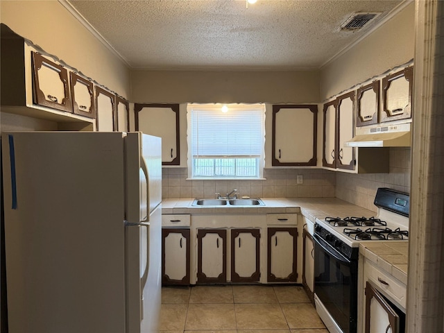 773 Lucky St, Houston, TX 77088 - kitchen with tile countertops, freestanding refrigerator, gas stove, under cabinet range hood, and a textured ceiling