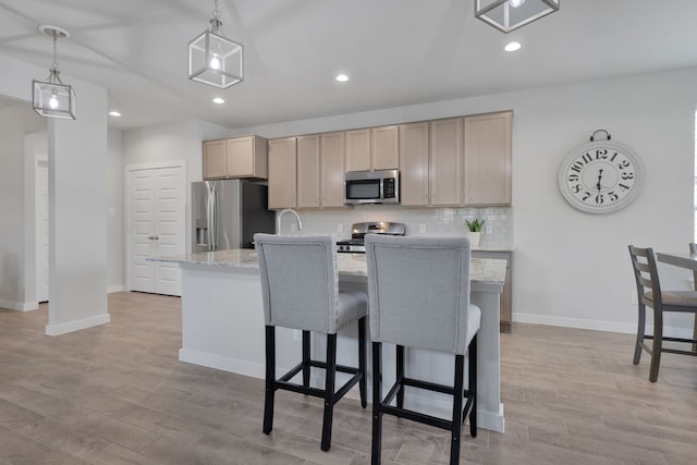 308 Spruce Oak Ln, Waller, TX 77484 - kitchen with stainless steel appliances, backsplash, an island with sink, baseboards, and light wood finished floors
