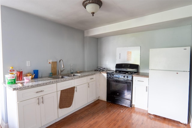 202 Booker T Washington St, Conroe, TX 77301 - kitchen featuring freestanding refrigerator, black range with gas cooktop, a sink, light wood-style flooring, and white cabinetry