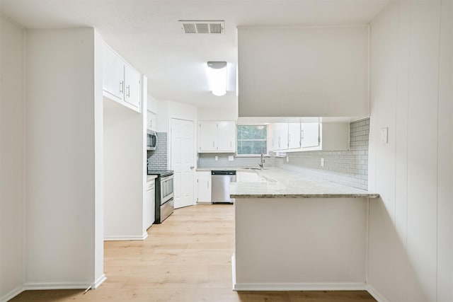 100 Harold Ln, Baytown, TX 77521 - kitchen featuring stainless steel appliances, a sink, a peninsula, decorative backsplash, and white cabinets