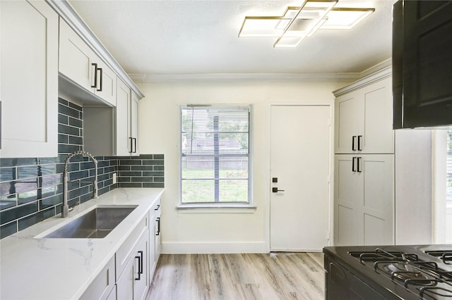 5326 Keystone St, Houston, TX 77021 - kitchen featuring a sink, light wood-style flooring, crown molding, decorative backsplash, and light stone countertops