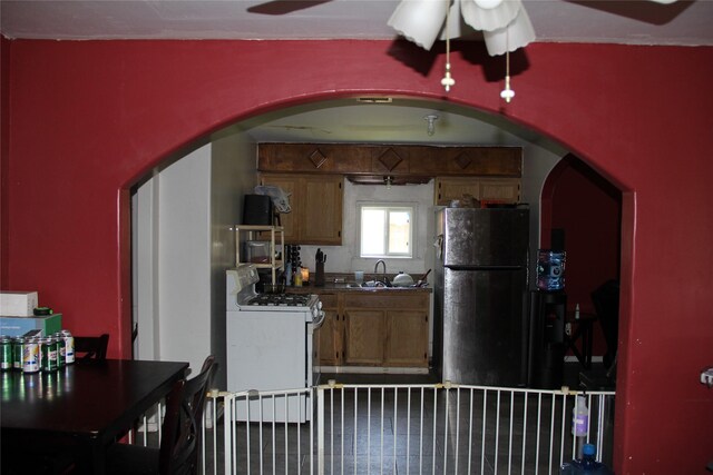 7615 Appleton St, Houston, TX 77022 - kitchen with white gas stove, freestanding refrigerator, arched walkways, and a ceiling fan