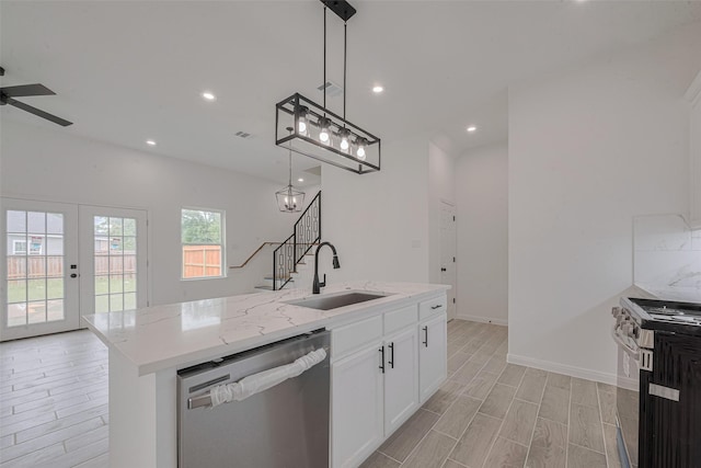 9212 Arvin St, Houston, TX 77028 - kitchen with stainless steel appliances, a sink, light wood finished floors, ceiling fan, and decorative light fixtures