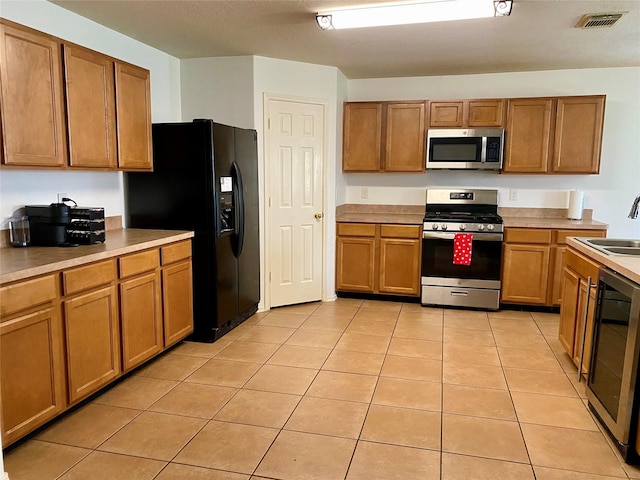19042 Yaupon Ranch Dr, Cypress, TX 77433 - kitchen with appliances with stainless steel finishes, brown cabinets, wine cooler, light tile patterned floors, and light countertops