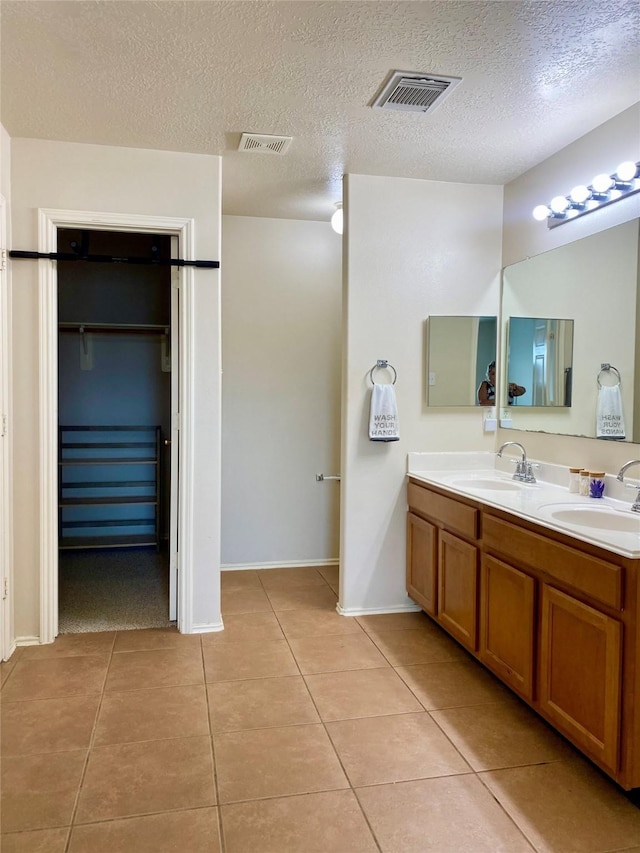 19042 Yaupon Ranch Dr, Cypress, TX 77433 - bathroom featuring tile patterned flooring, double vanity, a walk in closet, and a textured ceiling