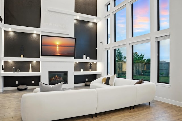 18011 Brazos River Cir, Cypress, TX 77433 - living room featuring a towering ceiling, baseboards, wood finished floors, a glass covered fireplace, and built in features