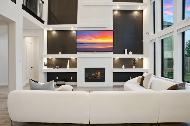 18011 Brazos River Cir, Cypress, TX 77433 - living area featuring wood finished floors, built in features, a glass covered fireplace, and a towering ceiling