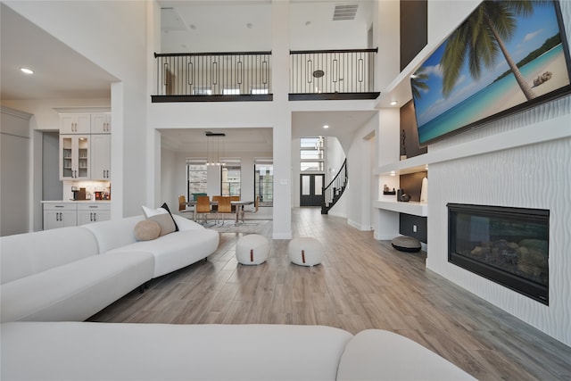 18011 Brazos River Cir, Cypress, TX 77433 - living area with stairs, wood finished floors, a high ceiling, a glass covered fireplace, and baseboards