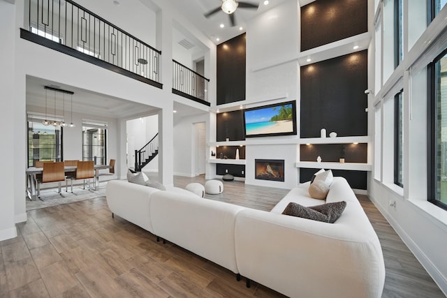 18011 Brazos River Cir, Cypress, TX 77433 - living area with a high ceiling, plenty of natural light, wood finished floors, a glass covered fireplace, and baseboards