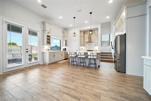 18011 Brazos River Cir, Cypress, TX 77433 - kitchen with wall chimney range hood, appliances with stainless steel finishes, a kitchen bar, a kitchen island, and decorative backsplash