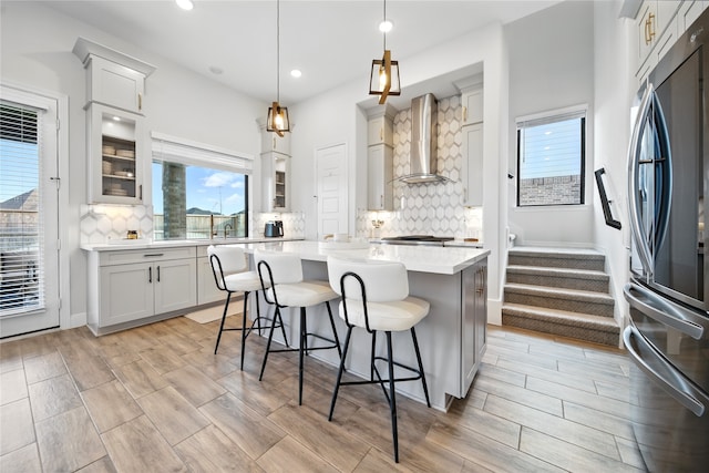 18011 Brazos River Cir, Cypress, TX 77433 - kitchen with wall chimney exhaust hood, stainless steel refrigerator, a breakfast bar, light countertops, and a kitchen island