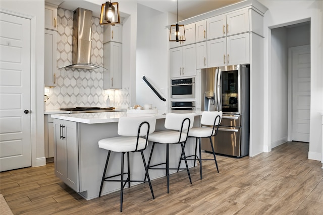 18011 Brazos River Cir, Cypress, TX 77433 - kitchen with appliances with stainless steel finishes, wall chimney exhaust hood, light countertops, light wood-style flooring, and tasteful backsplash