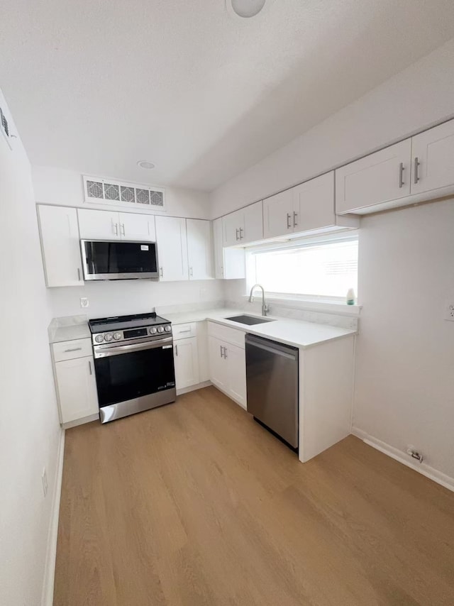 10855 Meadowglen Ln Unit 1121, Houston, TX 77042 - kitchen with stainless steel appliances, a sink, light wood-style flooring, and white cabinetry