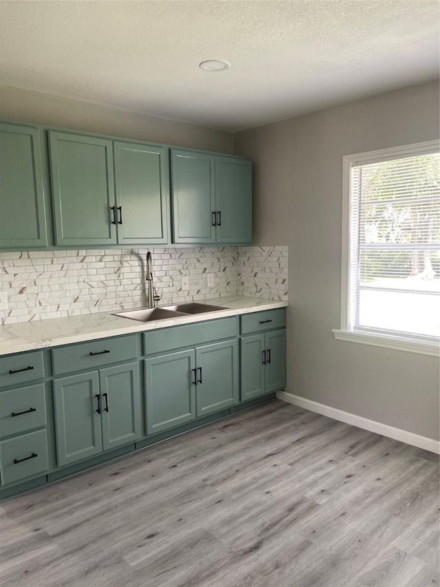 8630 Flossie Mae St, Houston, TX 77029 - kitchen with green cabinetry, a sink, decorative backsplash, light wood finished floors, and light countertops