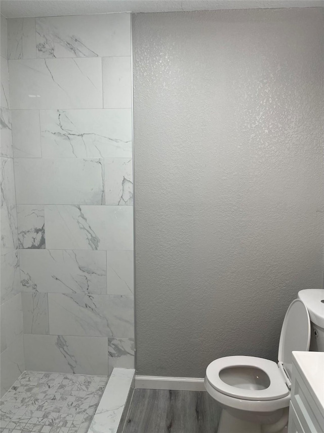 8630 Flossie Mae St, Houston, TX 77029 - bathroom with tiled shower, toilet, wood finished floors, vanity, and baseboards