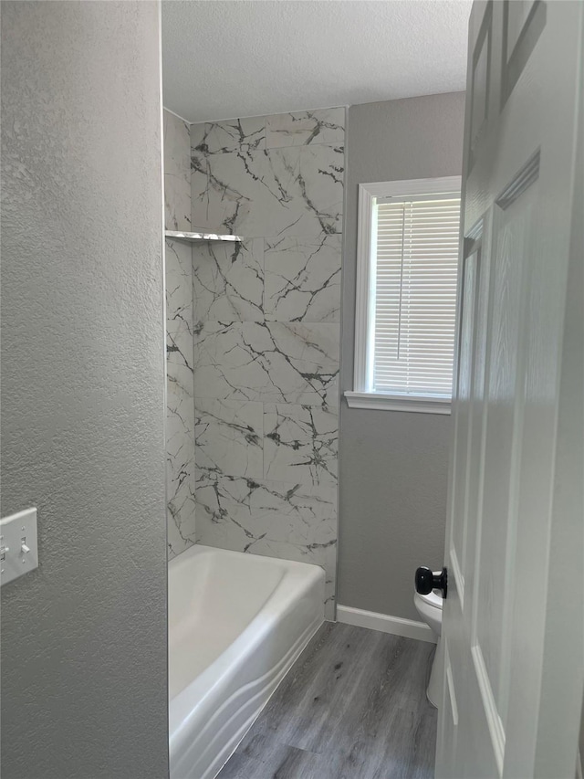 8630 Flossie Mae St, Houston, TX 77029 - bathroom with wood finished floors, toilet, shower / washtub combination, a textured ceiling, and baseboards