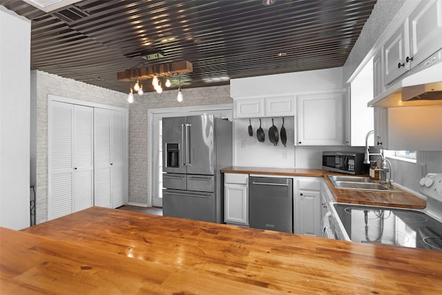 1137 Jones Rd, New Waverly, TX 77358 - kitchen with wood counters, appliances with stainless steel finishes, a sink, white cabinets, and extractor fan