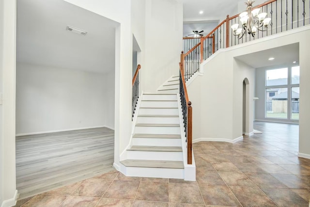 26122 Salt Creek Ln, Katy, TX 77494 - stairs featuring arched walkways, a towering ceiling, a ceiling fan, baseboards, and a chandelier