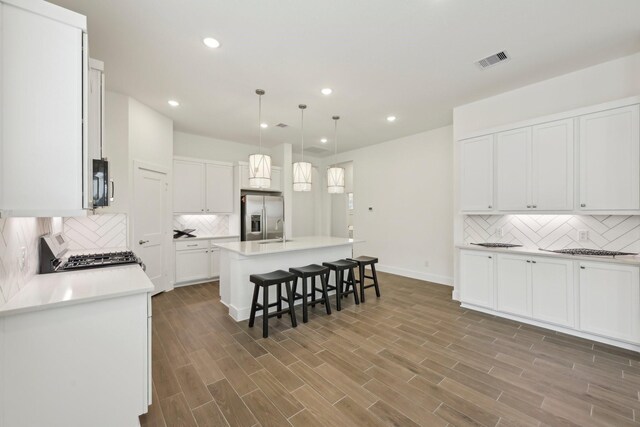 19265 Hazel Firs Ct, Magnolia, TX 77355 - kitchen with stainless steel refrigerator with ice dispenser, stove, backsplash, recessed lighting, and a kitchen bar