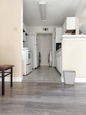 8443 Sands Point Dr, Houston, TX 77036 - kitchen featuring range, white cabinetry, light wood-style floors, and a textured ceiling
