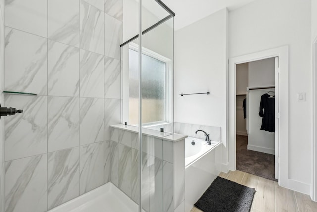 21517 Witham Promenade Ln, Magnolia, TX 77355 - bathroom featuring a garden tub, a shower stall, a walk in closet, and wood finished floors