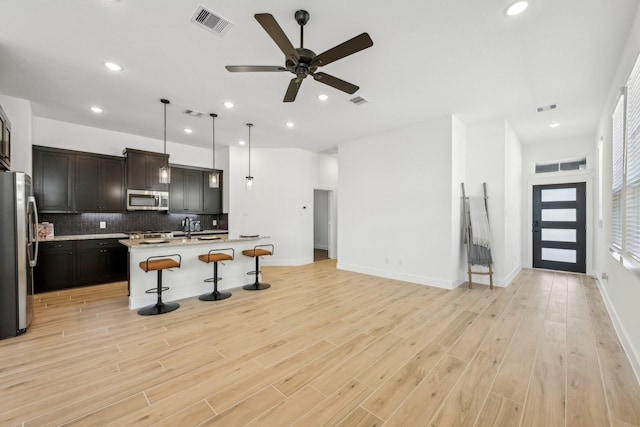21517 Witham Promenade Ln, Magnolia, TX 77355 - kitchen with appliances with stainless steel finishes, a kitchen breakfast bar, open floor plan, decorative backsplash, and ceiling fan