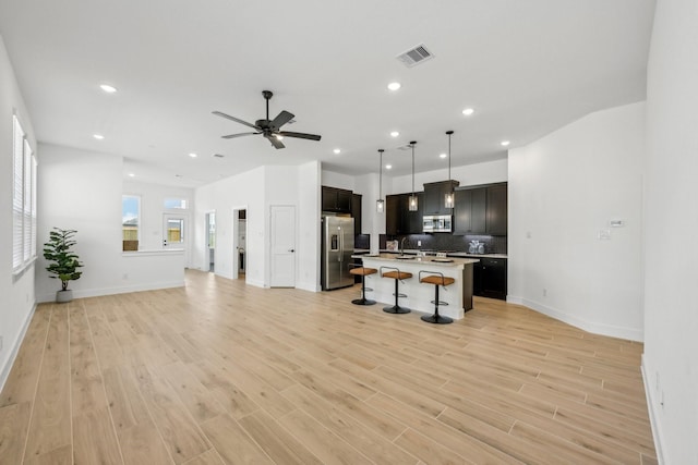 21517 Witham Promenade Ln, Magnolia, TX 77355 - kitchen with stainless steel appliances, open floor plan, a breakfast bar area, light countertops, and tasteful backsplash