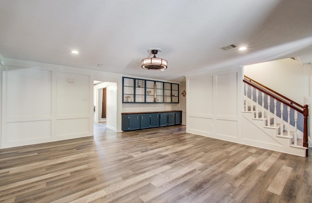 12103 Moorcreek Dr, Houston, TX 77070 - unfurnished living room with a decorative wall, stairway, wood finished floors, recessed lighting, and crown molding