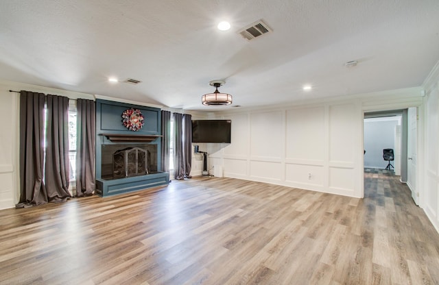 12103 Moorcreek Dr, Houston, TX 77070 - unfurnished living room with a decorative wall, ornamental molding, light wood finished floors, a fireplace with raised hearth, and recessed lighting