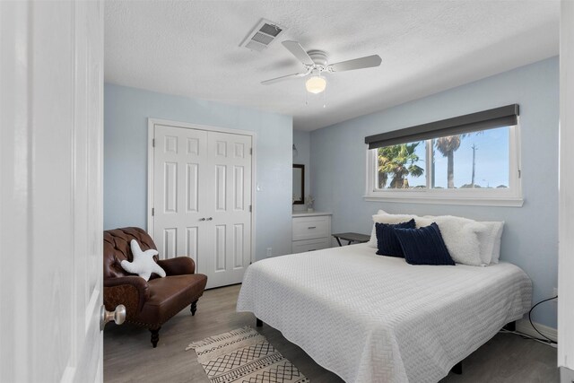 7600 Seawall Blvd Unit 109, Galveston, TX 77551 - bedroom with light wood-style flooring, a closet, ceiling fan, and a textured ceiling