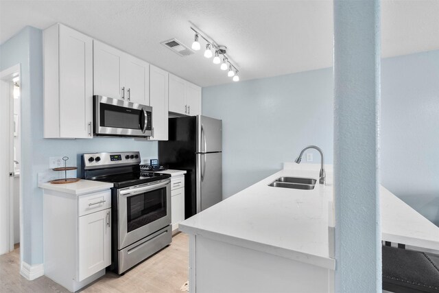 7600 Seawall Blvd Unit 109, Galveston, TX 77551 - kitchen with stainless steel appliances, a sink, light wood-style flooring, and white cabinetry