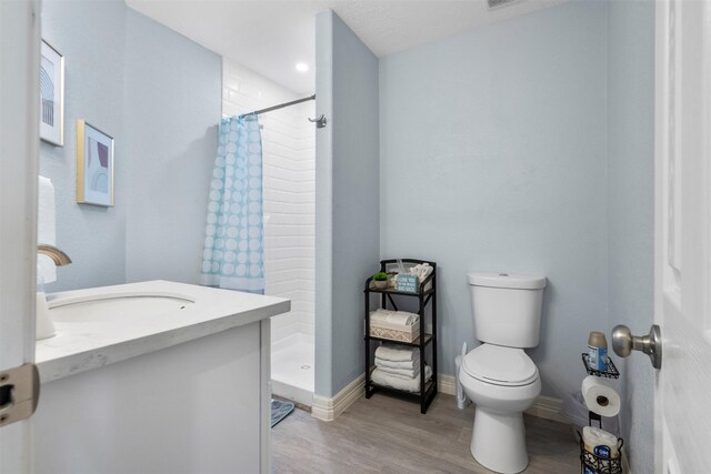 7600 Seawall Blvd Unit 109, Galveston, TX 77551 - full bathroom with toilet, a stall shower, wood finished floors, baseboards, and vanity