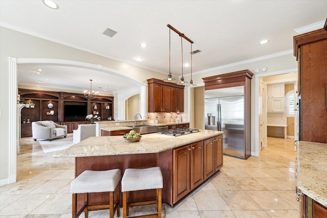 4911 Shiloh Lake Dr, Richmond, TX 77407 - kitchen featuring arched walkways, stainless steel appliances, a sink, light stone countertops, and decorative light fixtures