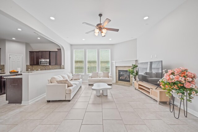 19918 Lizzie Ridge Ln, Cypress, TX 77433 - living area with a ceiling fan, recessed lighting, a tiled fireplace, light tile patterned floors, and arched walkways