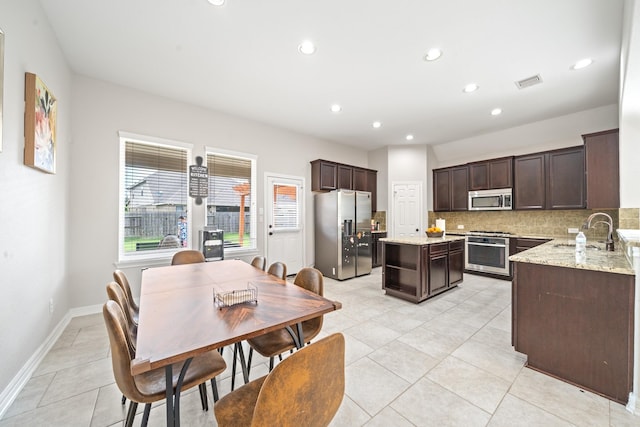 19918 Lizzie Ridge Ln, Cypress, TX 77433 - kitchen with appliances with stainless steel finishes, a sink, dark brown cabinetry, a kitchen island, and backsplash