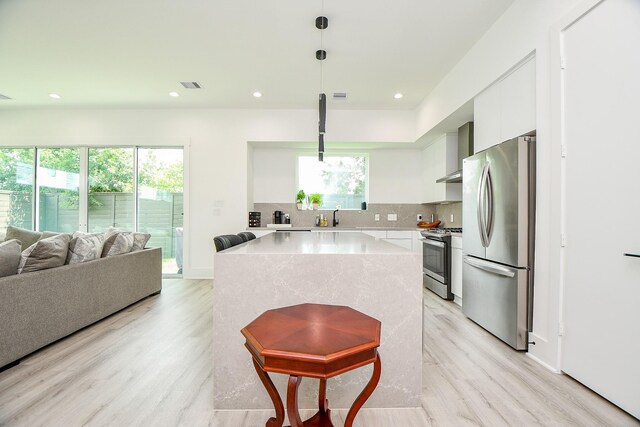 7603 Jacquelyn Gardens Ln, Houston, TX 77055 - kitchen with appliances with stainless steel finishes, modern cabinets, light wood-style flooring, a center island, and tasteful backsplash