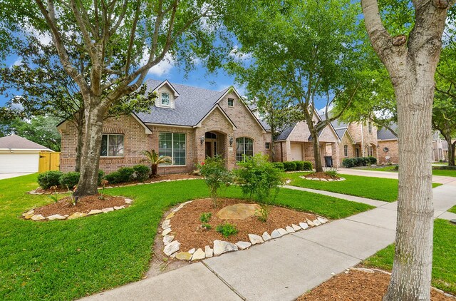 1511 Baldridge Ln, Katy, TX 77494 - traditional-style home featuring brick siding, a front yard, roof with shingles, and a garage