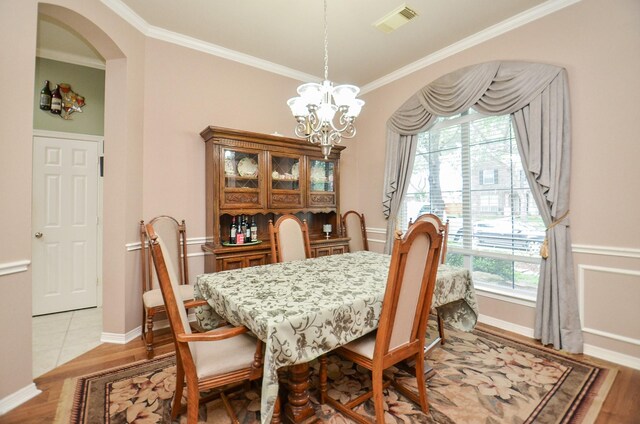 1511 Baldridge Ln, Katy, TX 77494 - dining room featuring a chandelier, crown molding, light wood finished floors, arched walkways, and baseboards