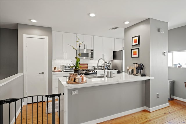 1716 W Dallas St Unit 11, Houston, TX 77019 - kitchen featuring stainless steel appliances, light wood finished floors, white cabinets, decorative backsplash, and light countertops